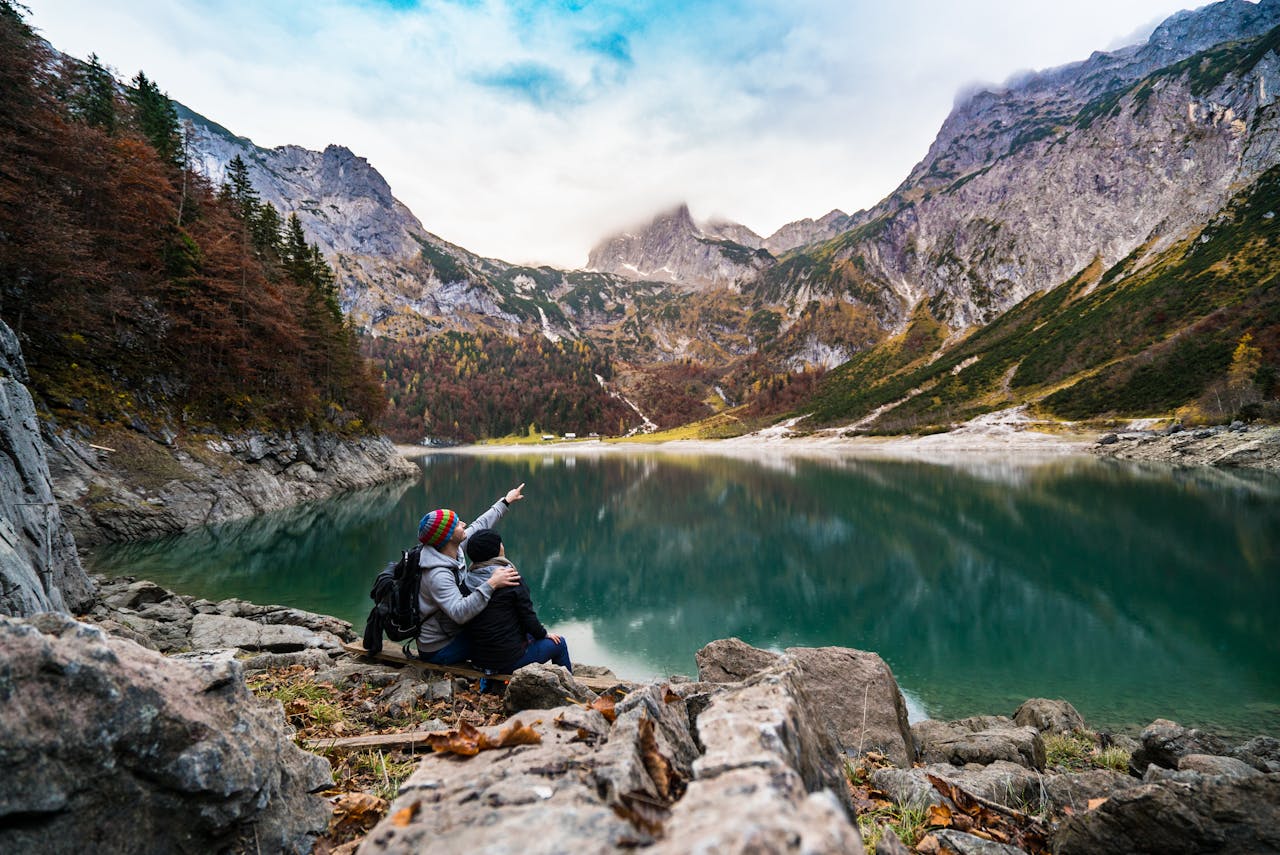 A couple enjoys a scenic view of Hallstatt Lake surrounded by mountains and fores.