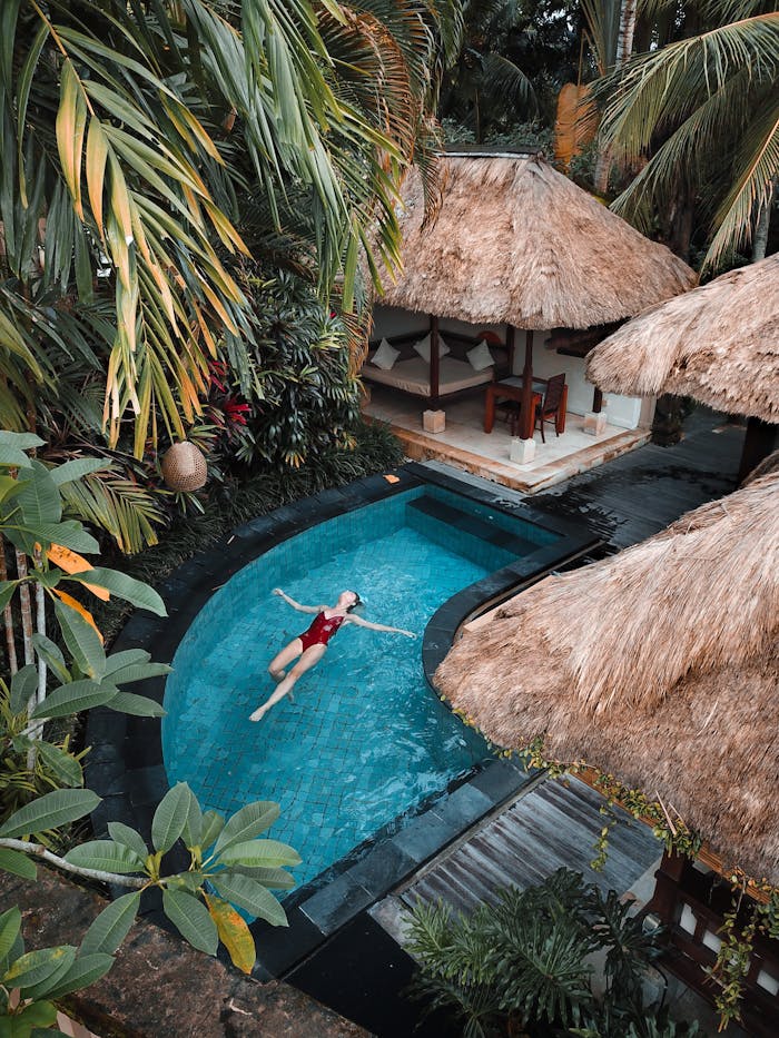 brand-03 A woman enjoying leisure time floating in a tropical resort pool surrounded by lush greenery.